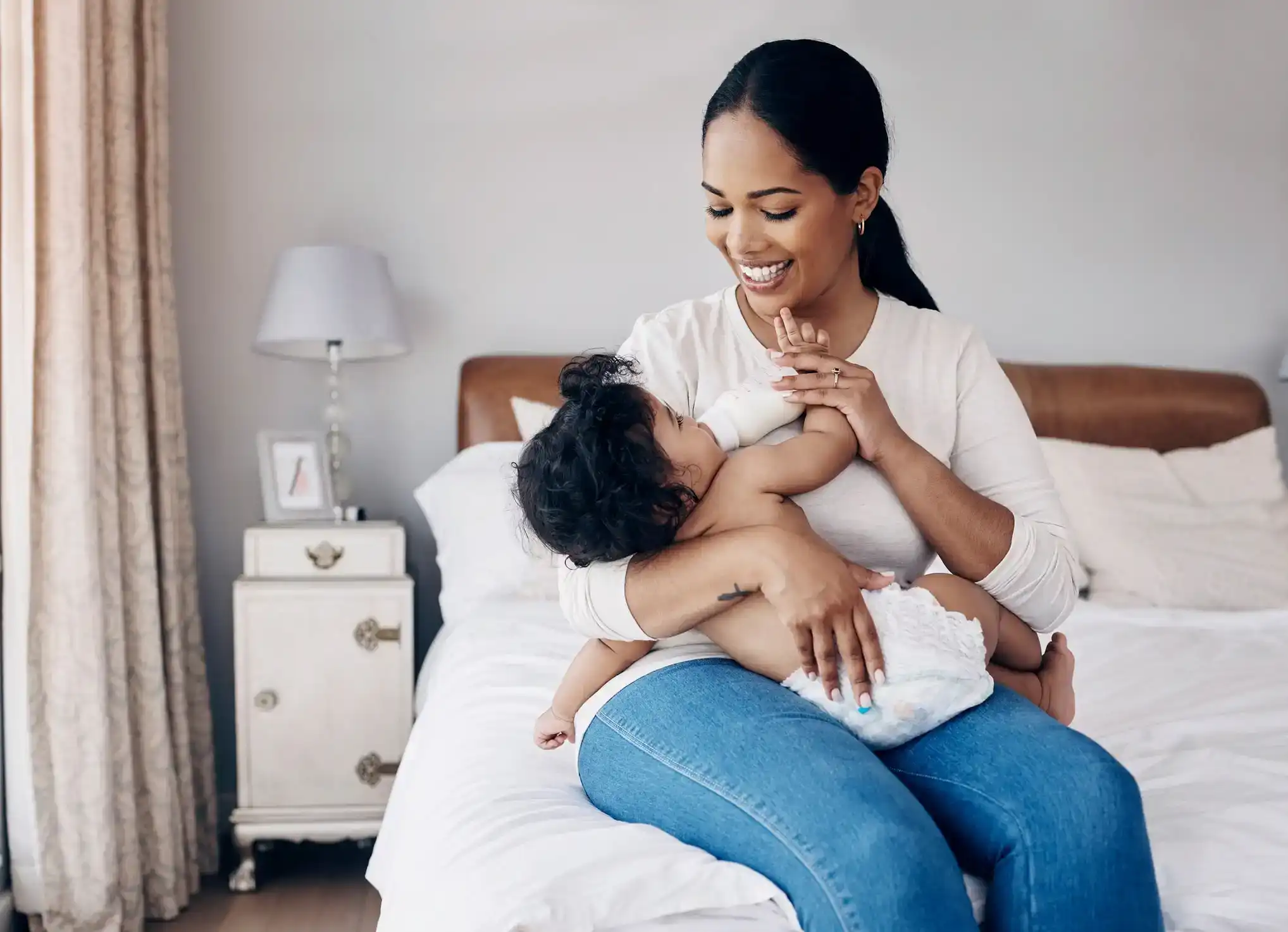 Mother feeds baby, smiling. Best baby bottle warmers