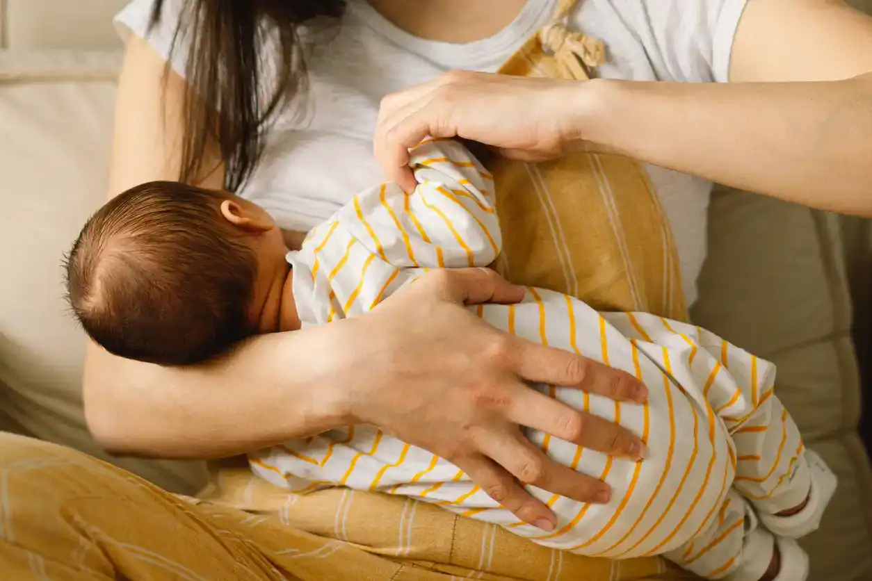 High angle portrait of young African-American mother breastfeeding cute baby boy with child looking at camera, copy space