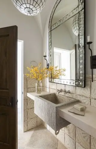Piccolo bagno con grande specchio, piastrelle beige e lavandino in pietra