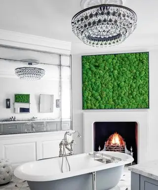 Un baño blanco con lámpara de araña, chimenea y obras de arte contemporáneas.
