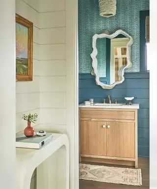 Vestiaire avec lambris bleus, papier peint bleu, meuble vasque en bois et miroir tendance