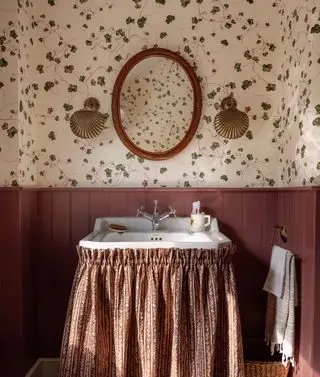 Une salle de bain vintage avec jupe de lavabo et lambris en tissu