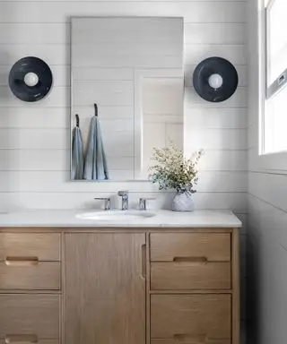 Salle de bain blanche avec lambris à feuillures et meuble vasque en bois