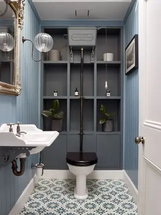 Un tocador azul con artículos sanitarios tradicionales, mosaicos y estanterías abiertas grises.