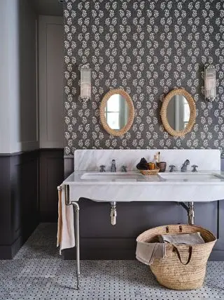 Baño gris con papel tapiz y lavabo doble con encimera de mármol.