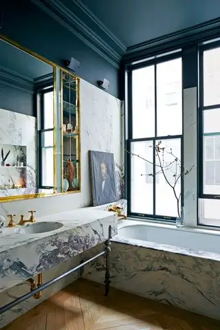 Cuarto de baño con bañera y tocador de mármol y techo negro.