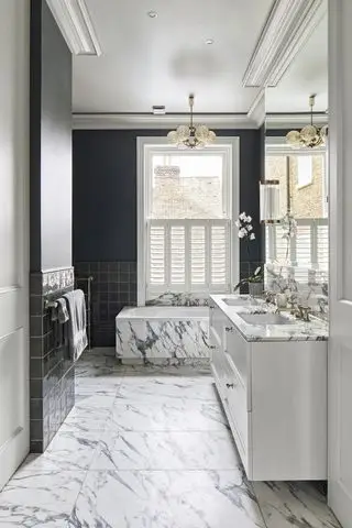 Baño blanco y negro con mármol y paredes oscuras.