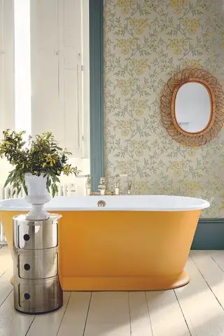 badeværelse med gulmalet badekar, tapet med gult blomsterdesign, fletspejl, metalopbevaring