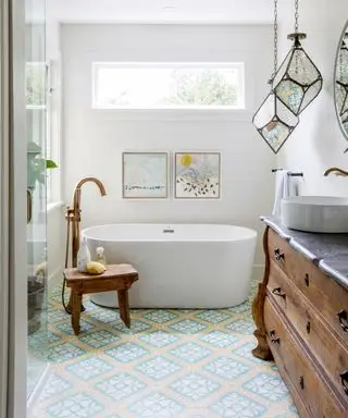 idées de salle de bains étroites, carrelage à motifs au sol, baignoire, tabouret et buffet vintage, borne-fontaine en laiton, pendentifs en verre