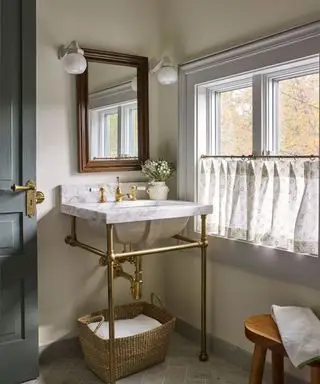 Petite salle de bains avec lavabo ouvert en laiton et rideau de café transparent