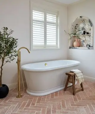 Salle de bain blanche avec carrelage en terre cuite et baignoire autoportante