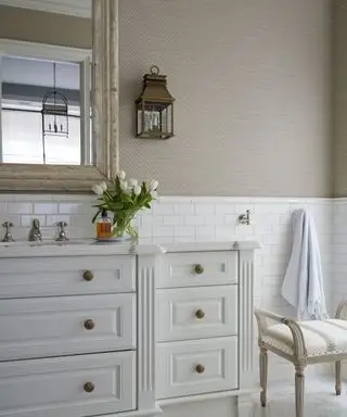 Salle de bains élégante avec papier peint en toile de jute et meuble sous-vasque traditionnel