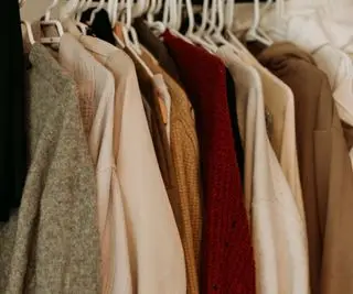 Vestiti di colore neutro appesi su una rotaia