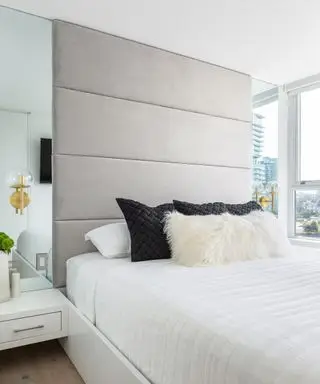 Ideen für Apartment-Schlafzimmer, illustriert mit verspiegelten Paneelen auf beiden Seiten des Bettes, die den Blick aus dem Fenster widerspiegeln