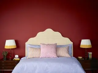 camera da letto rossa con lampade da comodino abbinate, testiera fantasia e cuscini