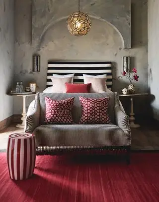 camera da letto con tappeto rosso, sgabello, cuscini, testiera del letto in bianco e nero, divano bianco e nero, comodini coordinati