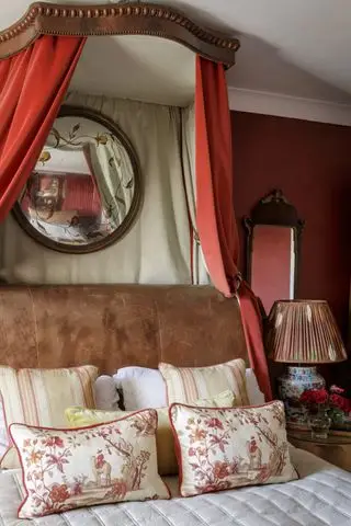 camera da letto con pareti rosse, baldacchino in tessuto rosso, letto in pelle