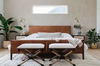 Dormitorio con paredes de yeso, cabecero de cuero y plantas de interior.
