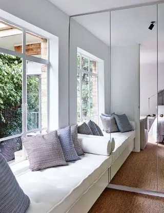 Pequeño vestidor con asientos y pared con espejos.