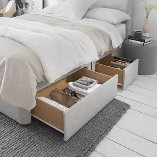 petite chambre avec rangement sous le lit, schéma neutre, plancher peint en blanc, tapis gris, lit gris pâle, repose-pieds/table de nuit gris moyen