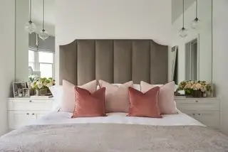 Chambre avec lit double avec tête de lit en velours et miroirs dans les alcôves de chaque côté