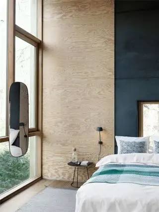 Un mur et un lit en contreplaqué à côté d'une grande baie vitrée.