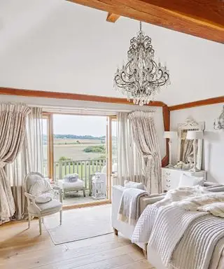 Una camera da letto in stile rustico con grande lampadario a candela e travi a vista