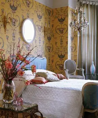 Una camera da letto con lampadario e carta da parati gialla in stile rococò