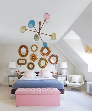 Un esempio di idee per un lampadario in camera da letto che mostra una camera da letto con un lampadario Sputnik con lampade multicolori sopra un letto blu e un contenitore imbottito rosa