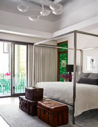 Ideas de dormitorio para hombres con cama con dosel y maletas vintage