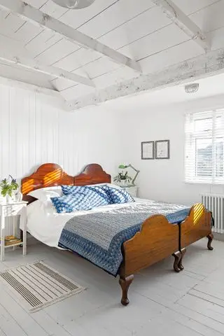 quarto branco com painéis shiplap, piso de madeira cinza e cama de madeira