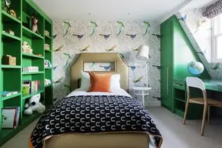 dormitorio para adolescentes con almacenamiento verde, papel tapiz de loro, persiana de cebra, escritorio, globo terráqueo, manta blanca y negra, almohada de cama naranja, cama individual dorada, mesa/luz blanca