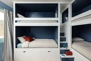 Dormitorio para chicos adolescentes con varias literas, interior azul, ropa de cama a rayas y cortinas a rayas azules.