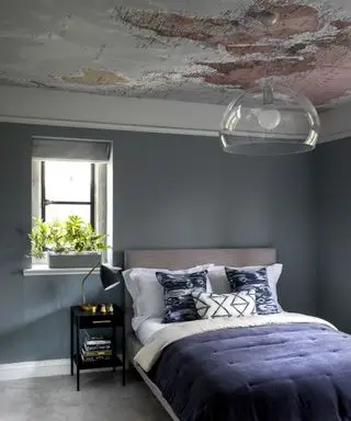 Una idea de dormitorio para adolescentes con pared azul, cama azul y papel tapiz de atlas en el techo.