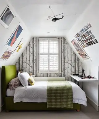 Una idea para el dormitorio de un adolescente en un loft con papel tapiz de bosque gris y blanco, modelos de aviones y carteles en las paredes.