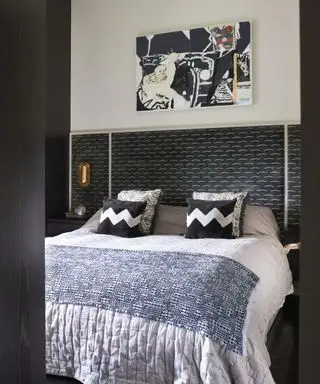 Una idea de dormitorio para adolescentes con cabecera negra con estampado de bigote blanco y paredes blancas.