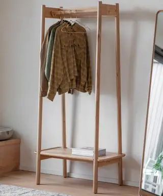 Kleidung hängt an einem Holzregal