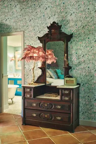 penteadeira vintage no quarto com papel de parede verde e vista do banheiro