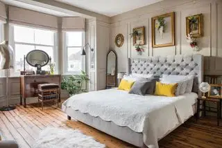 camera da letto vintage con boiserie, testiera capitonnè e cornici vintage a parete