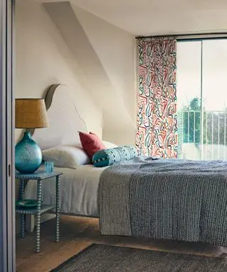 letto con testiera gialla e biancheria da letto patchwork contro un muro accanto a una finestra