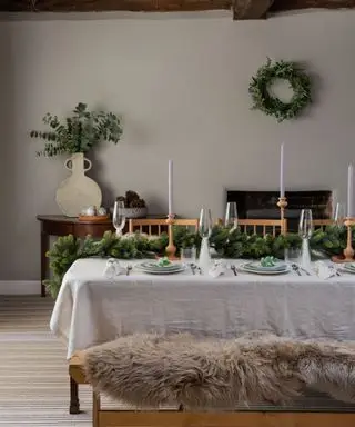 Uma mesa de jantar rústica simples com guirlanda verde e castiçais