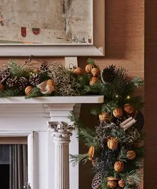 Decoração de manto de Natal com guirlanda de laranjas secas, canela e pinhas