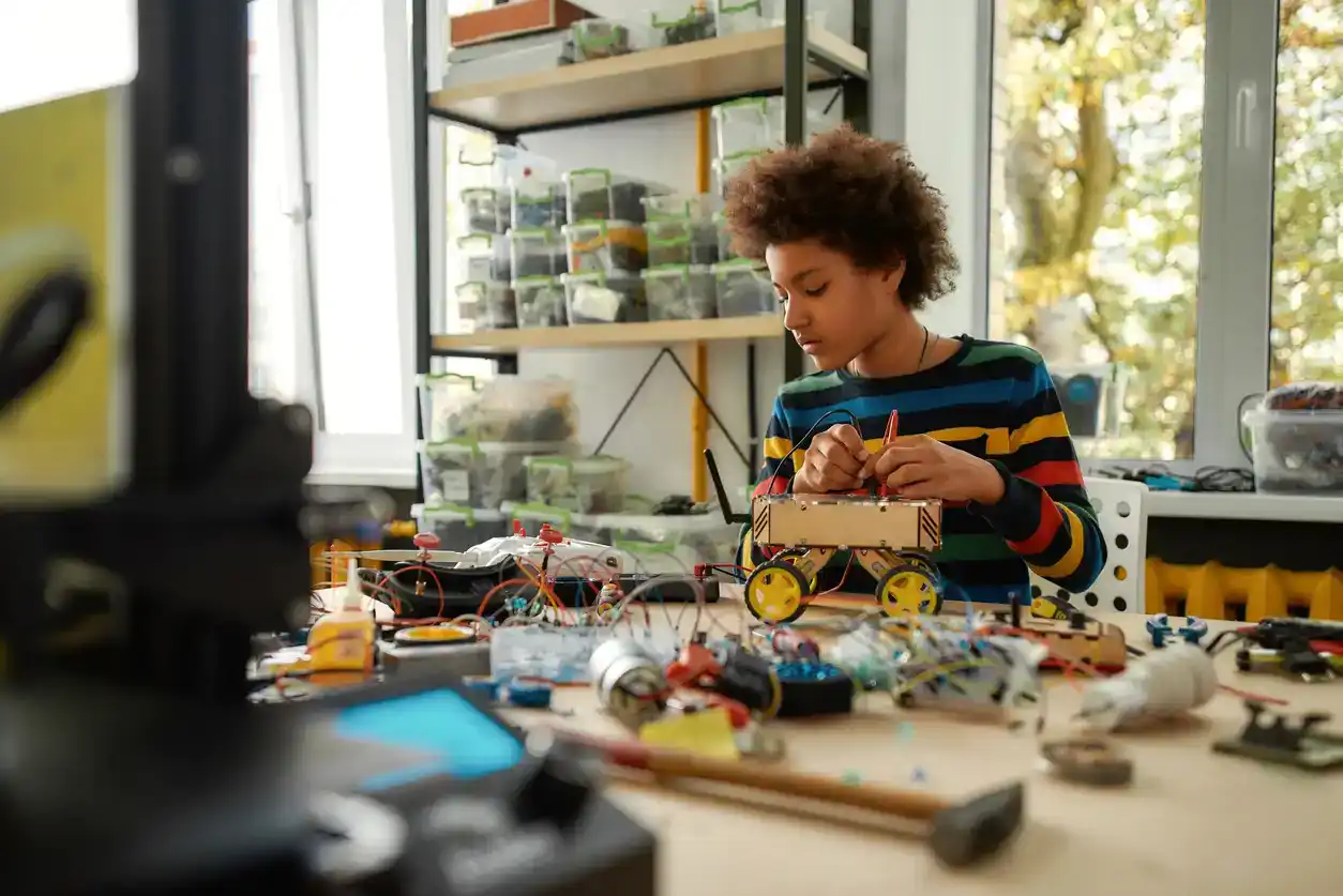 Child programming, testing robot vehicle, working with wires and circuits at stem class. Robotics and software engineering for elementary students. Horizontal shot