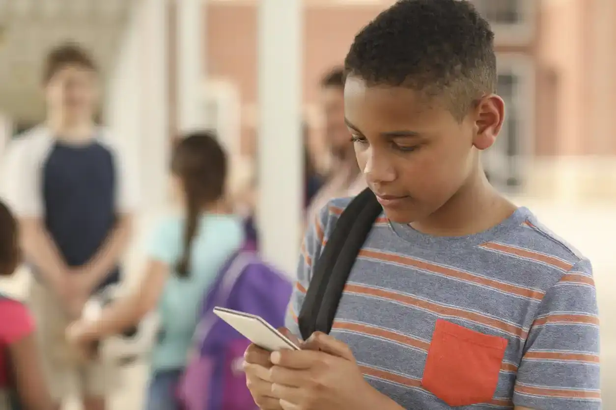 Middle school boy uses his phone in school, on Discord