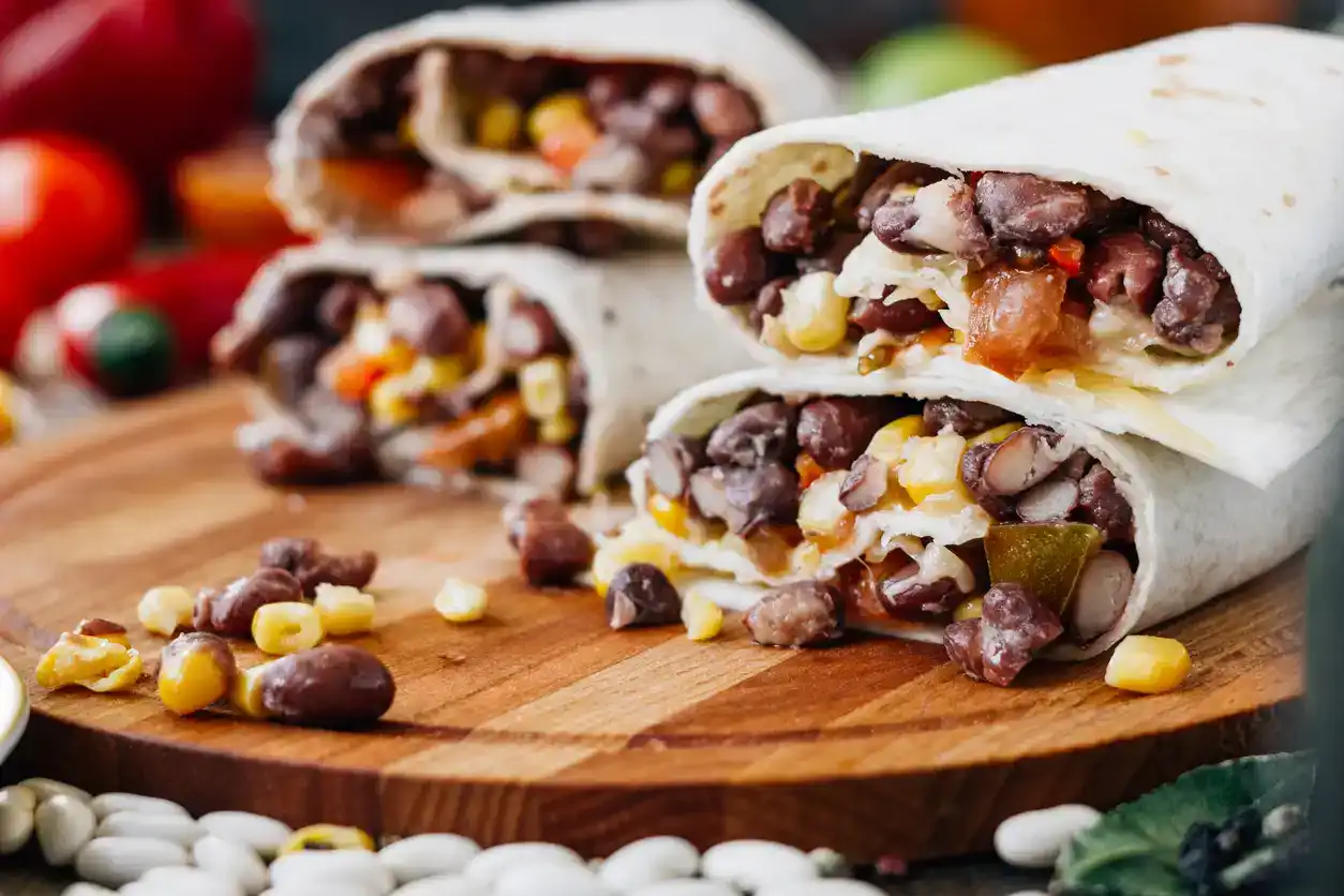 Nice vegetarian burrito over black table on wooden board