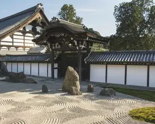 Un esempio di idee per un giardino giapponese che mostra un sentiero di ghiaia accanto all'edificio di un tempio