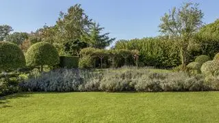 Prato verde rigoglioso con aiuole di lavanda e alberi di arte topiaria
