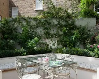 Terrasseplantningsideer med indbygget siddeplads og spisebord i en byhave.