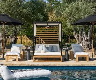 lettino da esterno coperto e mobili coordinati accanto a una piscina
