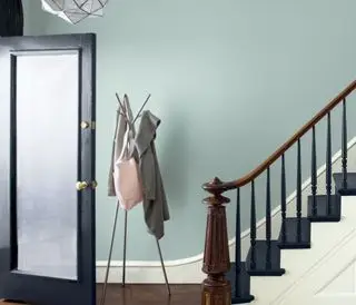 Puerta de entrada y escalera con peldaños pintados y pared gris